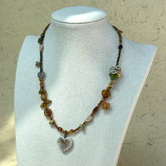 Full view of Heart of Leaves Necklace styled with vintage paper props