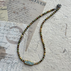 Close-up of turquoise-patterned talisman bead on earthy seed bead strand