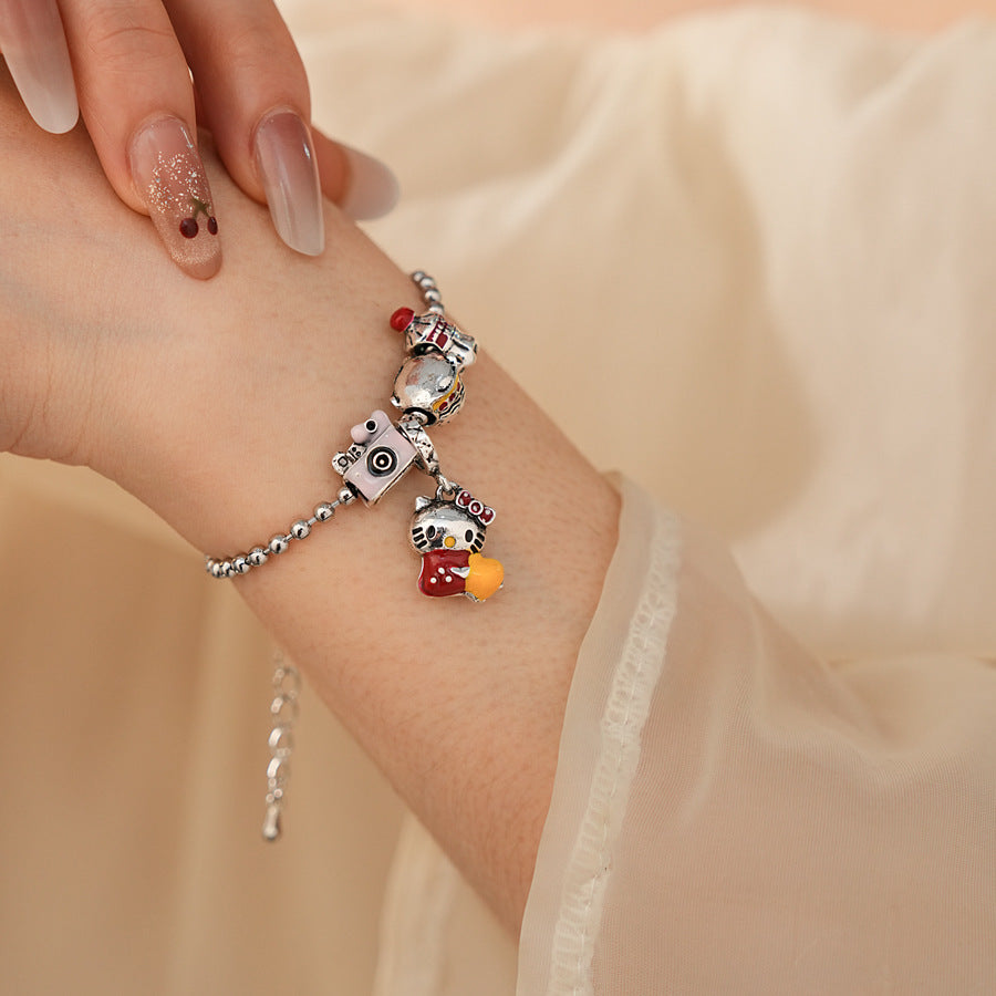 Kawaii Charm Story Bracelet with cartoon cat, burger, camera, and bell charms on silver-tone bead chain