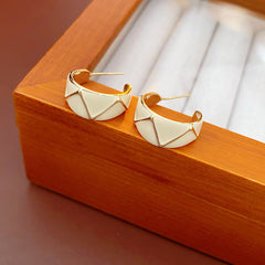 Set of four geometric enamel hoop earrings in white, blue, coffee, and green displayed in a jewelry tray