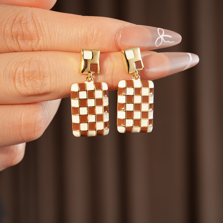 Gilded Mosaic Drop Earrings in two colors — geometric enamel checker tiles with gold-plated frame, Midnight Blue and Mocha Ivory, silver post dangle design on jewelry tray
