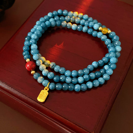 Blue multi-wrap beaded bracelet with red accent bead and gold charm — Azure Charm Wrap Bracelet.