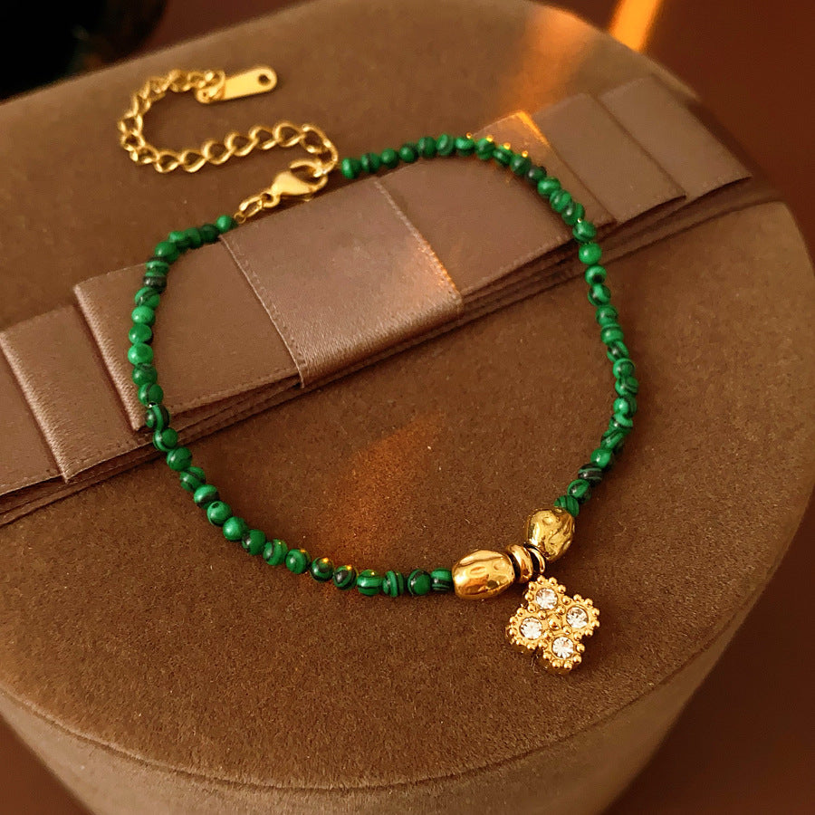 Two variant options of a malachite charm bracelet: beaded green strand with a crystal bloom charm, and a gold-tone chain with malachite accents and a heart pendant — Malachite Charm Bracelet (Variants).
