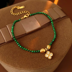 Two variant options of a malachite charm bracelet: beaded green strand with a crystal bloom charm, and a gold-tone chain with malachite accents and a heart pendant — Malachite Charm Bracelet (Variants).