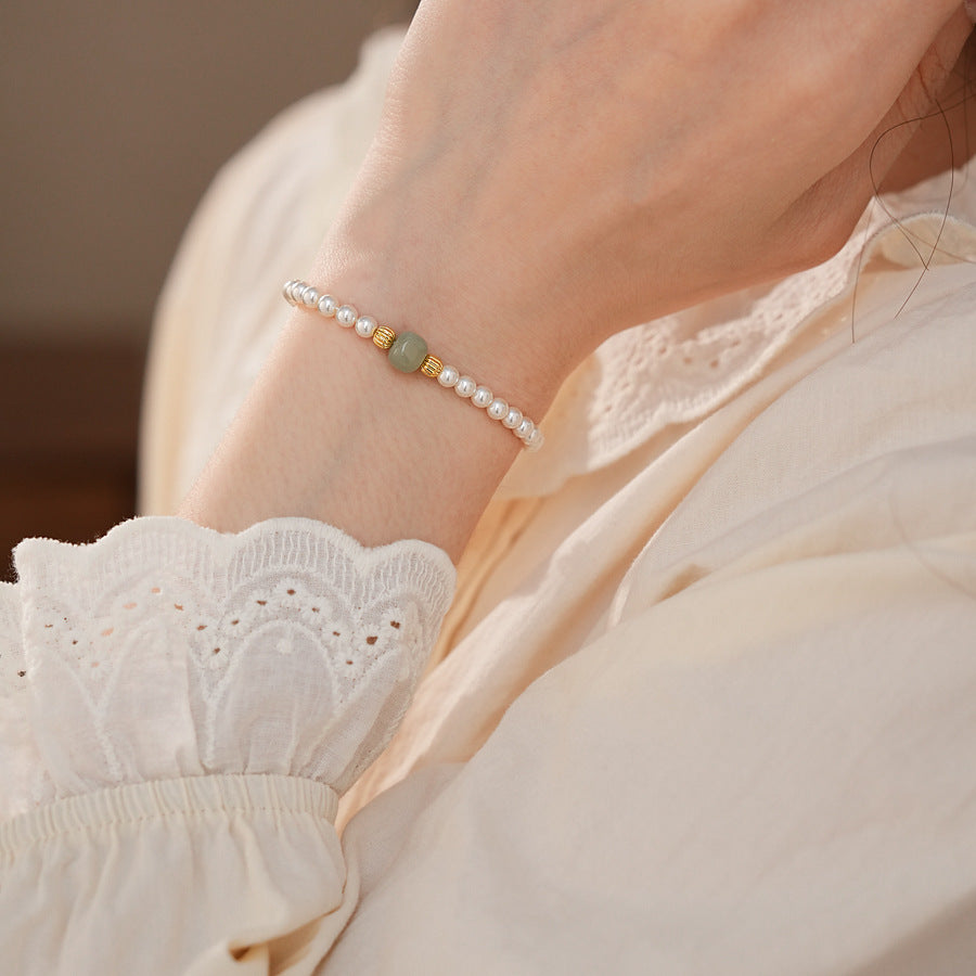 Delicate pearl bracelet with a pale green Hetian jade focal bead and gold-tone spacers — Hetian Jade Pearl Bracelet.