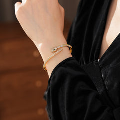 Gold and silver snake-shaped zircon bangles with emerald eyes — Serpent Luxe Bangle by Glazenya.