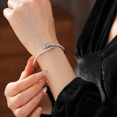 Gold and silver snake-shaped zircon bangles with emerald eyes — Serpent Luxe Bangle by Glazenya.
