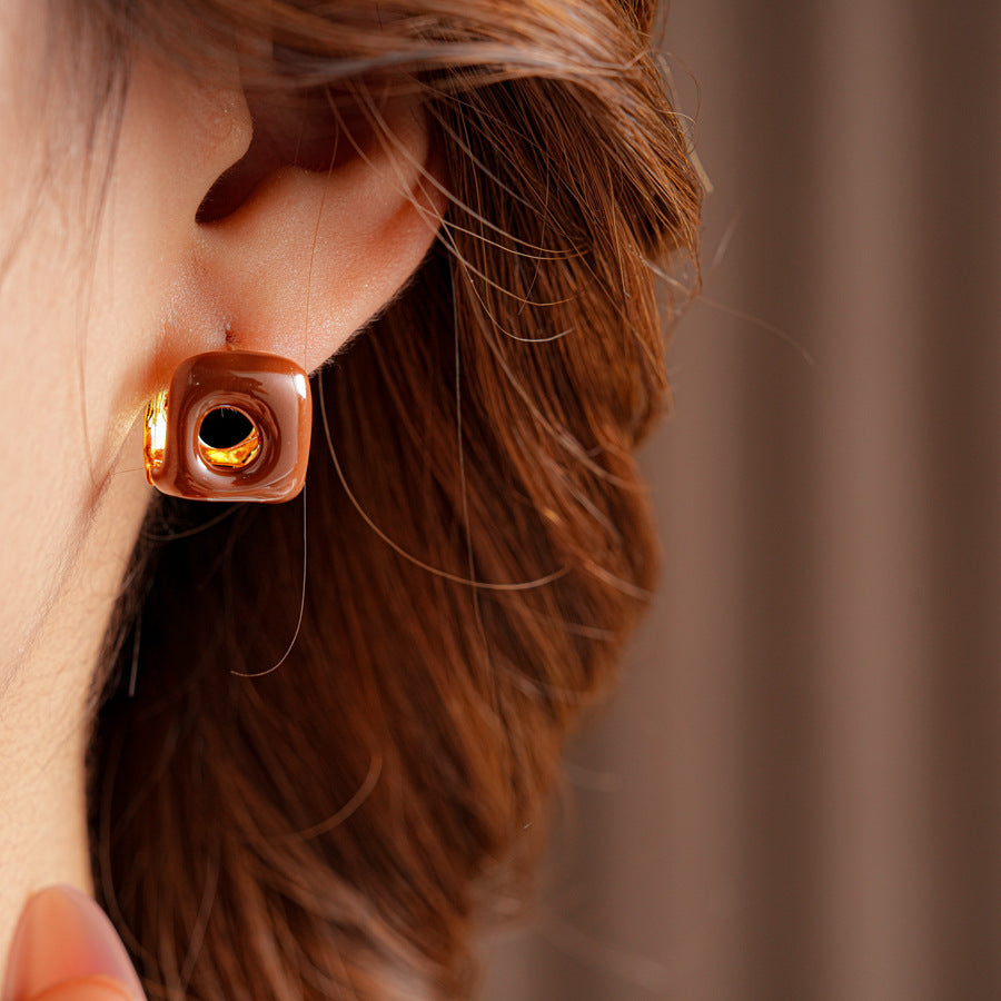 Square pillow ear cuffs with glossy enamel shell and mirrored gold core in white, red, and coffee — Gilded Core Pillow Ear Cuffs.