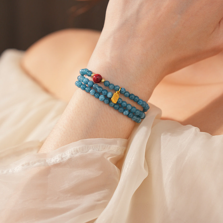 Blue multi-wrap beaded bracelet with red accent bead and gold charm — Azure Charm Wrap Bracelet.
