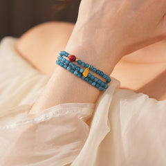 Blue multi-wrap beaded bracelet with red accent bead and gold charm — Azure Charm Wrap Bracelet.