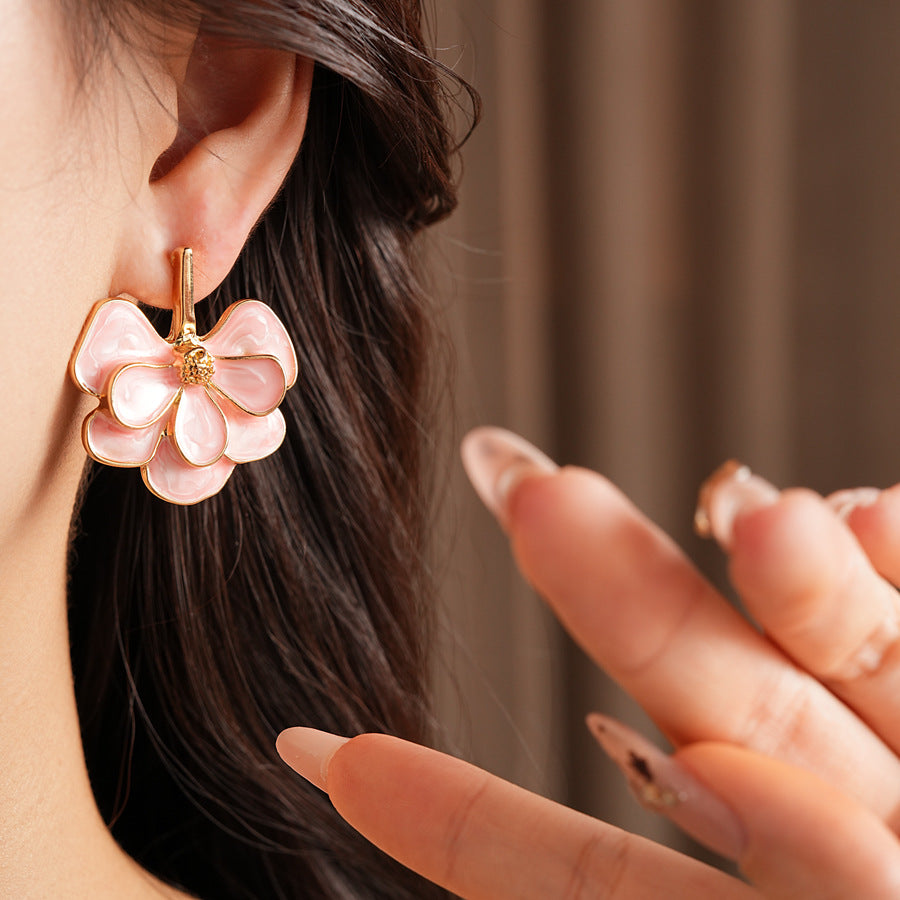 Close-up of pink enamel flower earrings with gold tone petals, statement design on jewelry tray