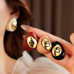 Matte pebble stud earrings with mirrored gold dome engraved with 5 — in white, black, coffee, and red — Gilded Numeral 5 Pebble Studs.