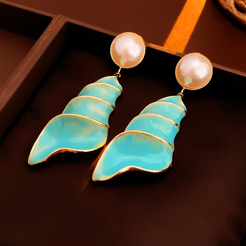 Lagoon Spiral Pearl Drop Earrings — glossy turquoise spiral shell drops with pearl studs and gold trim on jewelry tray