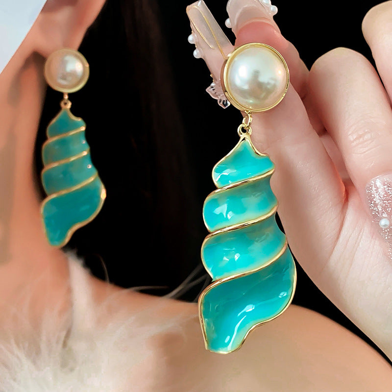 Lagoon Spiral Pearl Drop Earrings — glossy turquoise spiral shell drops with pearl studs and gold trim on jewelry tray