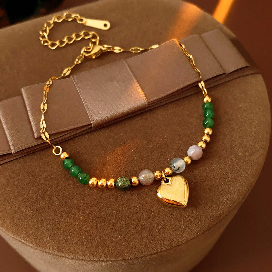 Two variant options of a malachite charm bracelet: beaded green strand with a crystal bloom charm, and a gold-tone chain with malachite accents and a heart pendant — Malachite Charm Bracelet (Variants).