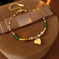 Two variant options of a malachite charm bracelet: beaded green strand with a crystal bloom charm, and a gold-tone chain with malachite accents and a heart pendant — Malachite Charm Bracelet (Variants).