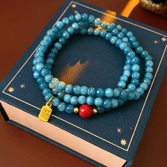Blue multi-wrap beaded bracelet with red accent bead and gold charm — Azure Charm Wrap Bracelet.