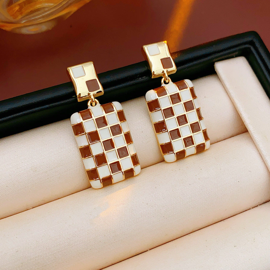 Gilded Mosaic Drop Earrings in two colors — geometric enamel checker tiles with gold-plated frame, Midnight Blue and Mocha Ivory, silver post dangle design on jewelry tray