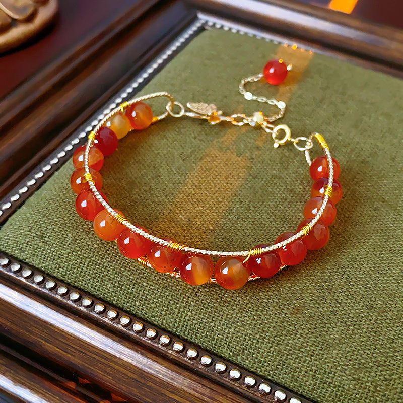 Natural stone beaded bracelets in multiple colors including red agate, rose quartz, and white crystal, with golden accents displayed in a jewelry tray.