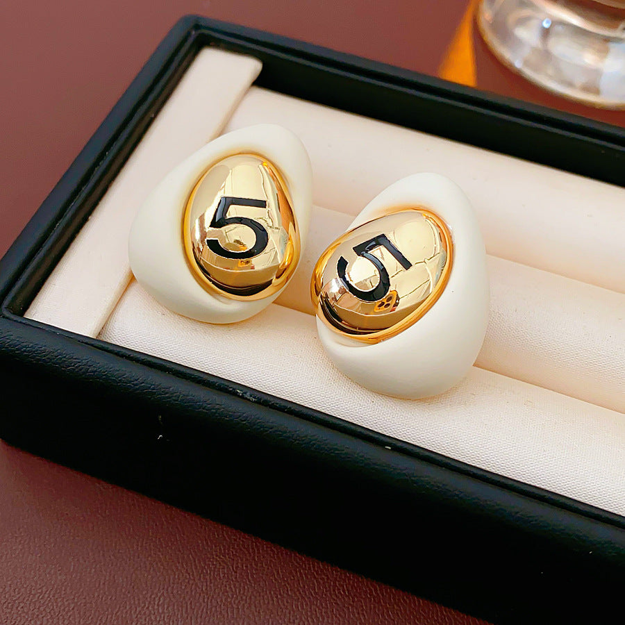 Matte pebble stud earrings with mirrored gold dome engraved with 5 — in white, black, coffee, and red — Gilded Numeral 5 Pebble Studs.