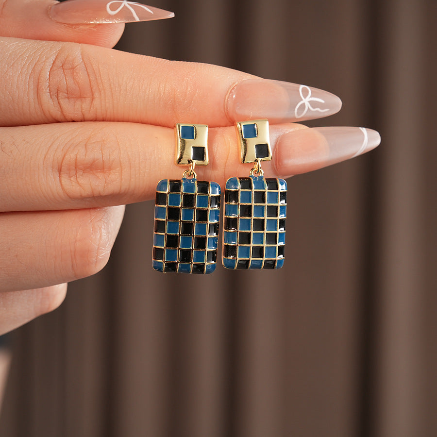 Gilded Mosaic Drop Earrings in two colors — geometric enamel checker tiles with gold-plated frame, Midnight Blue and Mocha Ivory, silver post dangle design on jewelry tray