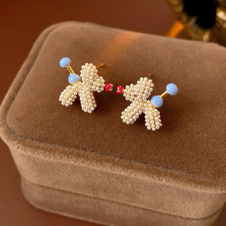 Balloon dog stud earrings crafted from imitation pearls with blue bead details — Playful Poodle Pearl Studs.