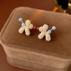 Balloon dog stud earrings crafted from imitation pearls with blue bead details — Playful Poodle Pearl Studs.