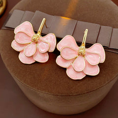Close-up of pink enamel flower earrings with gold tone petals, statement design on jewelry tray