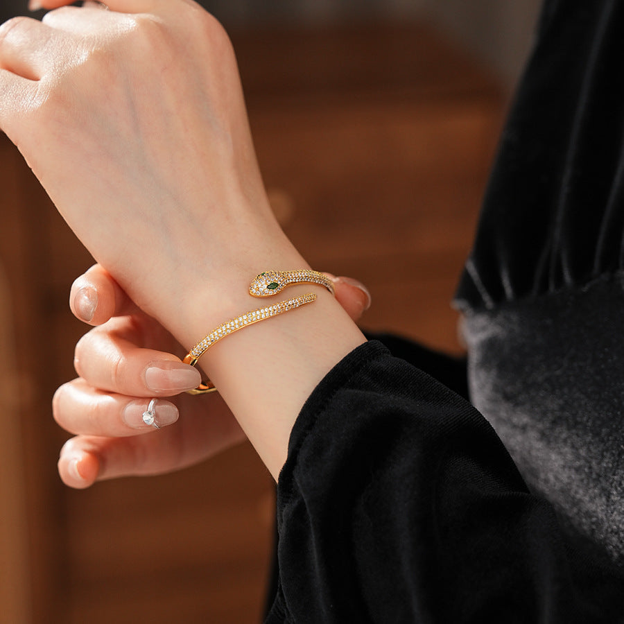 Gold and silver snake-shaped zircon bangles with emerald eyes — Serpent Luxe Bangle by Glazenya.
