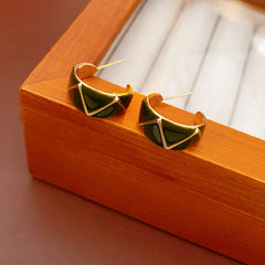 Set of four geometric enamel hoop earrings in white, blue, coffee, and green displayed in a jewelry tray