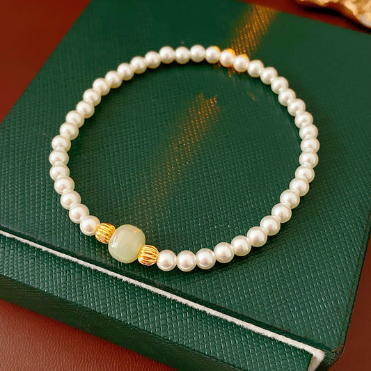 Delicate pearl bracelet with a pale green Hetian jade focal bead and gold-tone spacers — Hetian Jade Pearl Bracelet.