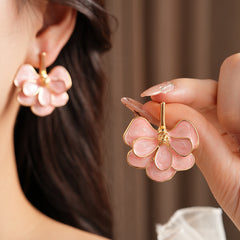 Close-up of pink enamel flower earrings with gold tone petals, statement design on jewelry tray