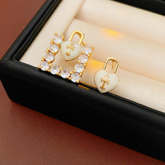 Enamel heart-lock and rhinestone square padlock mismatched stud earrings in gold tone.
