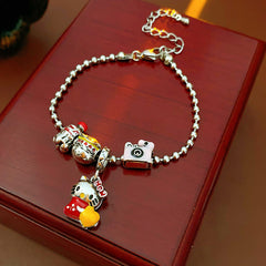 Kawaii Charm Story Bracelet with cartoon cat, burger, camera, and bell charms on silver-tone bead chain