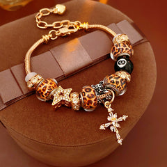 Leopard Cross Luxe Bracelet with leopard-patterned beads, zircon accents, black 8-ball bead, and cross pendant on gold chain