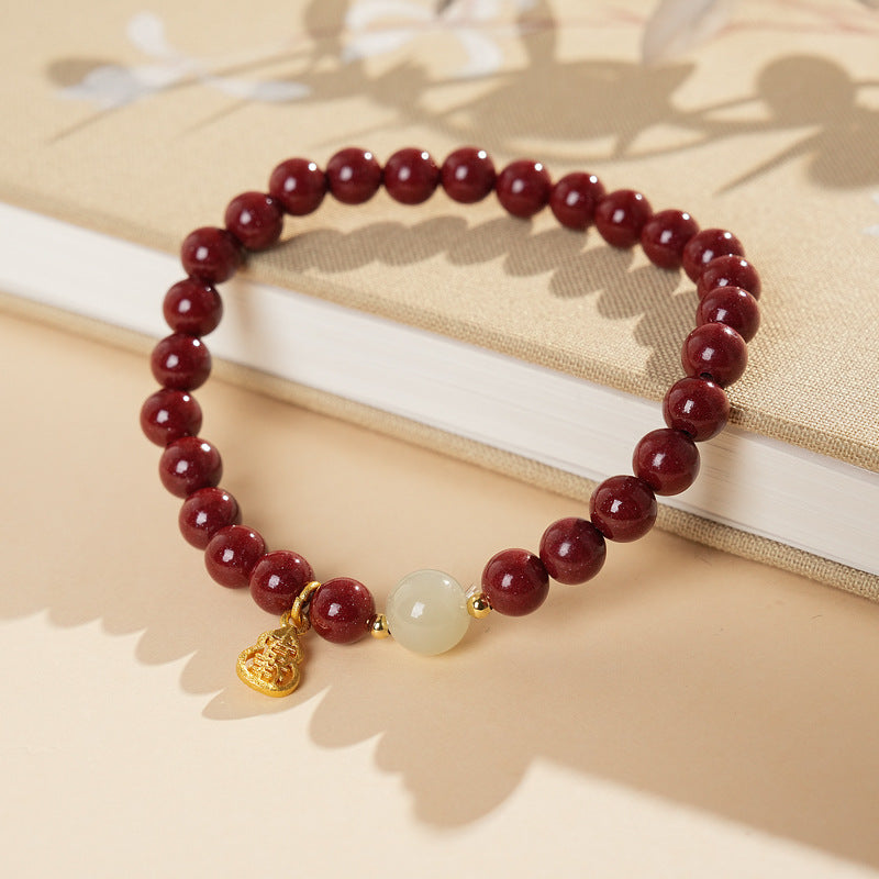Red cinnabar beaded bracelet with Hetian jade bead and a gold-tone gourd charm.