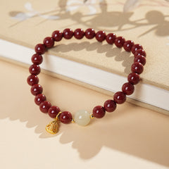 Red cinnabar beaded bracelet with Hetian jade bead and a gold-tone gourd charm.