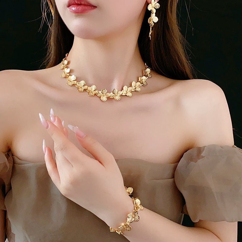 Golden Petal Elegance Set with necklace, bracelet, and earrings featuring golden floral petal details