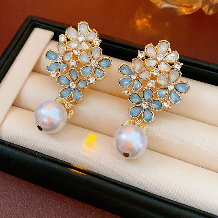 Gold floral cluster earrings with ice-blue petals, crystal accents, and a single luminous faux-pearl drop — Ethereal Petal Pearl Earrings.