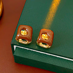 Square pillow ear cuffs with glossy enamel shell and mirrored gold core in white, red, and coffee — Gilded Core Pillow Ear Cuffs.