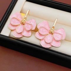 Close-up of pink enamel flower earrings with gold tone petals, statement design on jewelry tray