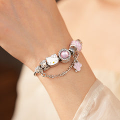 Rosy Pawprints Charm Bracelet — silver-tone snake chain with pink crystal bezel, checker enamel bead, cat-with-bow, paw and bone charms in jewelry tray
