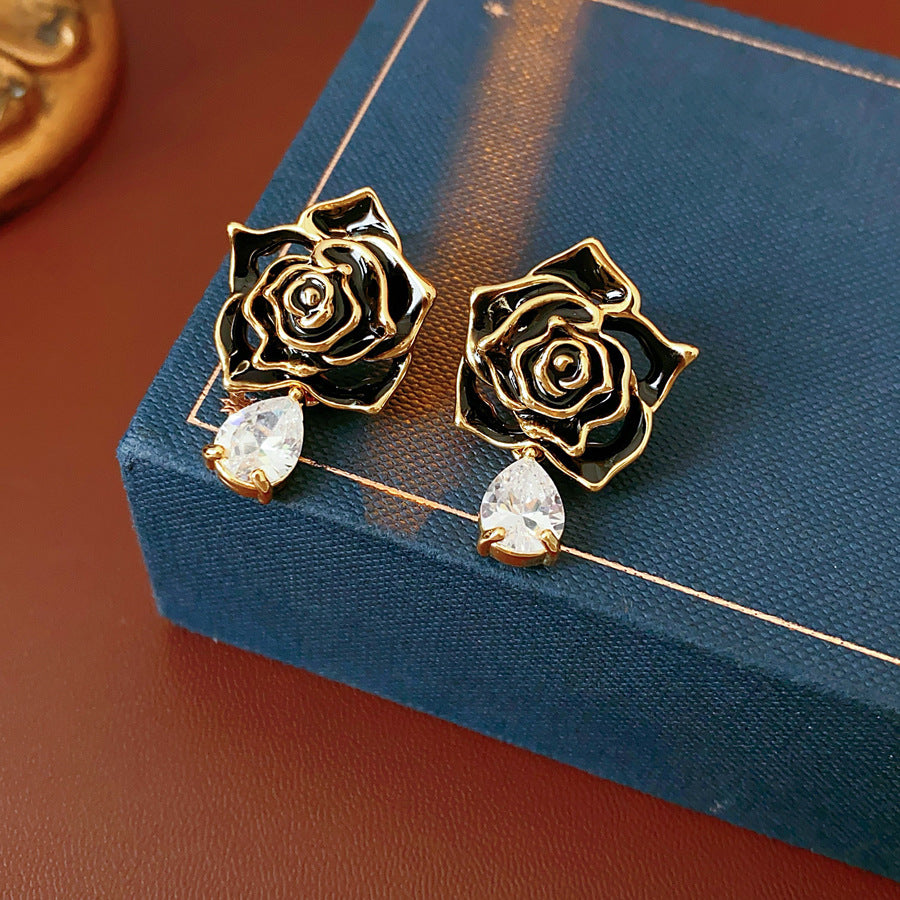 Gold-tone rose stud earrings with ivory and black enamel petals plus teardrop zircon dangles — Gilded Rose Teardrop Studs.