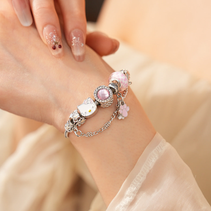 Rosy Pawprints Charm Bracelet — silver-tone snake chain with pink crystal bezel, checker enamel bead, cat-with-bow, paw and bone charms in jewelry tray