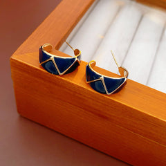 Set of four geometric enamel hoop earrings in white, blue, coffee, and green displayed in a jewelry tray