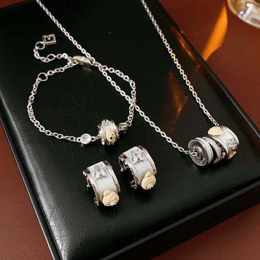 Ivory Glow Barrel Charm Collection — white enamel barrel-bead necklace, bracelet and right-ear cuff on black jewelry box, silver-tone chains with zircon details