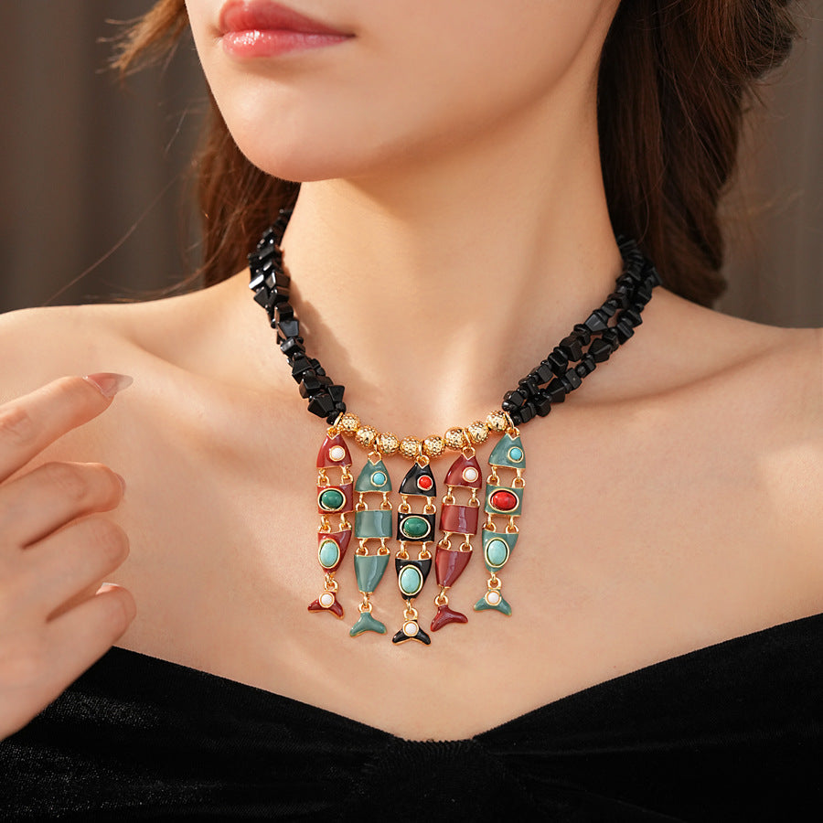 Statement necklace with articulated fishbone fringe, gold beads, and red or black chip strands — Kaleido Fishbone Fringe Necklace.
