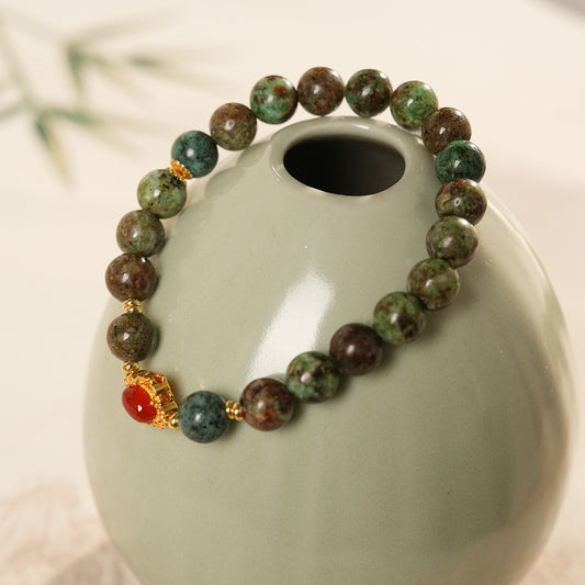 <div class="gz-desc">
  <p>Earthy and refined <strong>natural stone bracelet</strong> combining lush <strong>green ghost</strong> beads with smooth <strong>agate</strong>, accented by a warm red centerpiece and gold-tone spacers for a subtle touch of luxury.</p>

  <h3>Design Story</h3>
  <p>The <strong>Forest Ember Agate Bracelet</strong> evokes the calm of an ancient forest lit by a single ember. Mossy green tones bring grounding energy, while the red accent adds a gentle spark—balance between serenity an