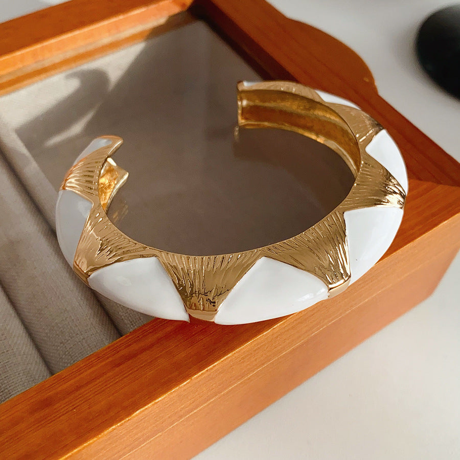 Gold-tone open cuff with triangular glossy enamel peaks; three variants (black, white, red) — Harlequin Enamel Cuff.