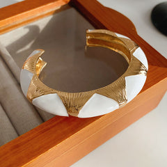 Gold-tone open cuff with triangular glossy enamel peaks; three variants (black, white, red) — Harlequin Enamel Cuff.